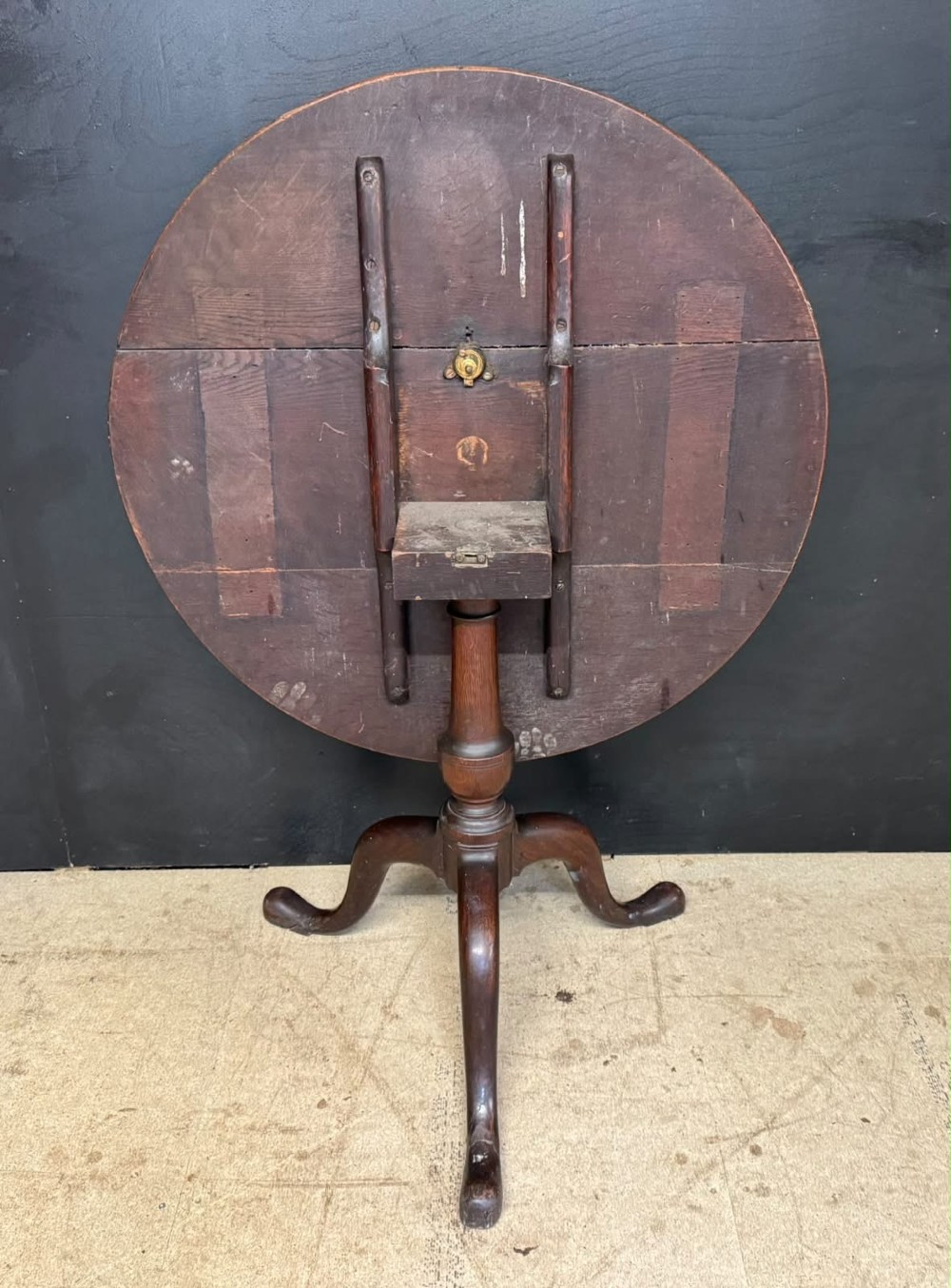 An antique circular oak tilt-top table featuring a three-plank top mounted on a turned pedestal column with three curved tripod legs. View III
