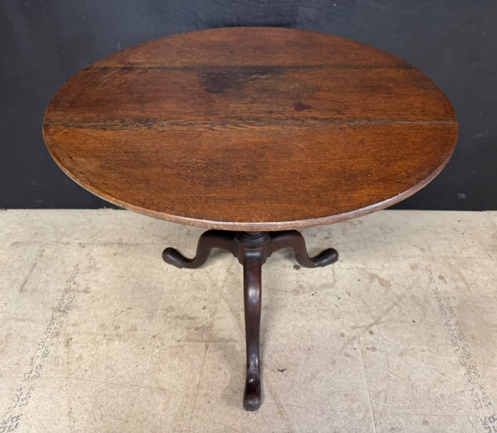 An antique circular oak tilt-top table featuring a three-plank top mounted on a turned pedestal column with three curved tripod legs. View VIII