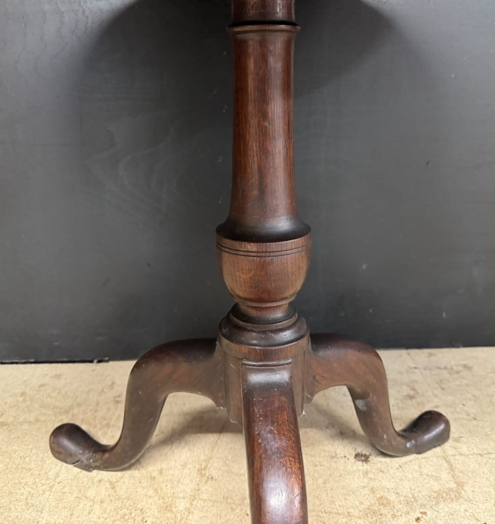 An antique circular oak tilt-top table featuring a three-plank top mounted on a turned pedestal column with three curved tripod legs. View X