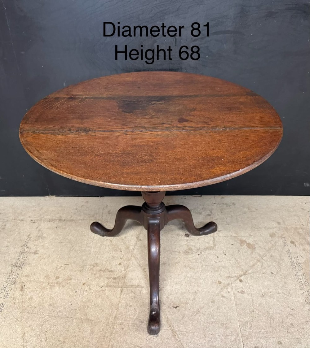 An antique circular oak tilt-top table featuring a three-plank top mounted on a turned pedestal column with three curved tripod legs. View XI