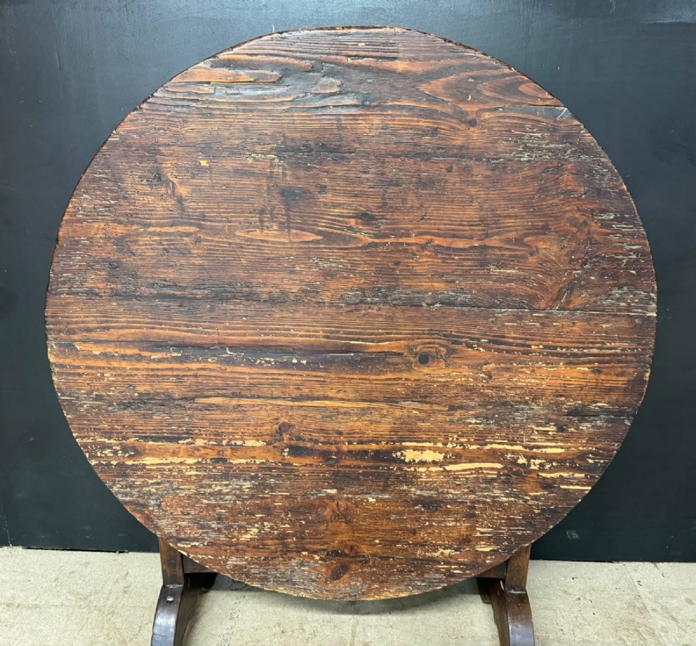 A circular French wine tasting table made of dark warm brown timber shown in a tilted position on a trestle base. View II