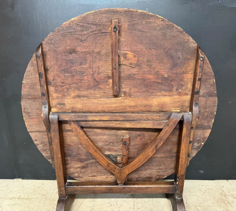 A circular French wine tasting table made of dark warm brown timber shown in a tilted position on a trestle base. View IV