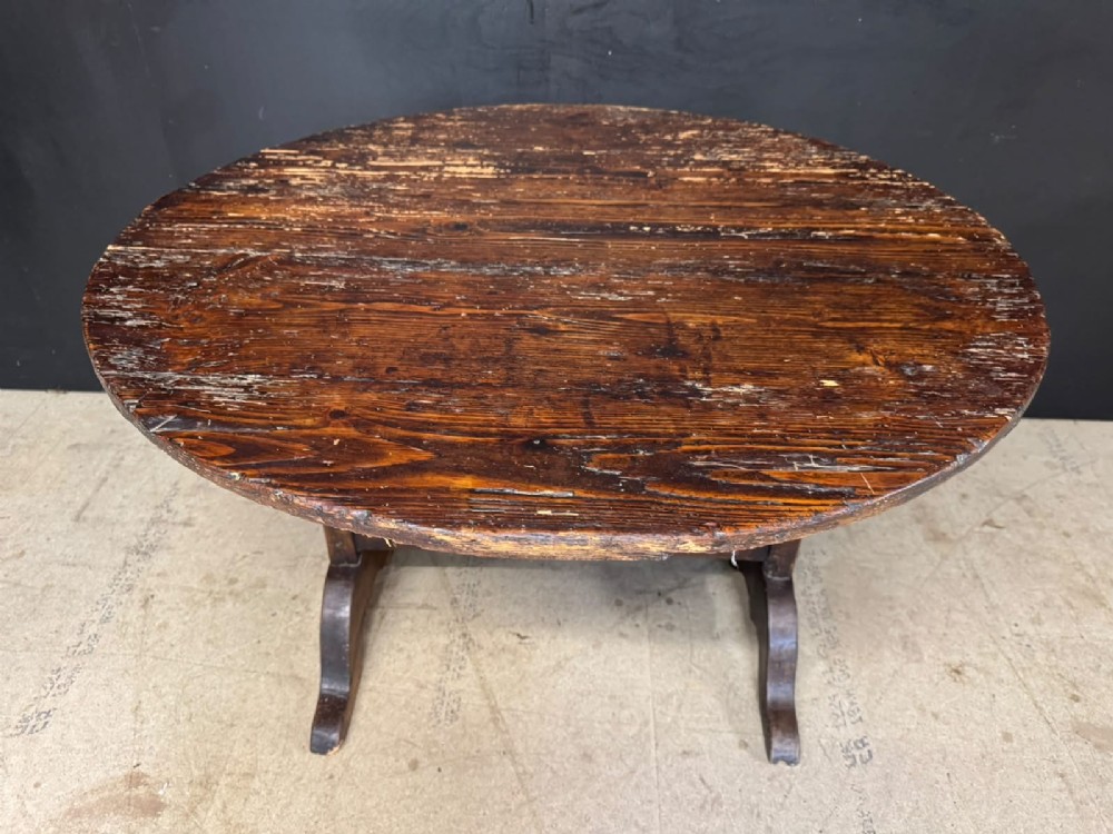 A circular French wine tasting table made of dark warm brown timber shown in a tilted position on a trestle base. View VI