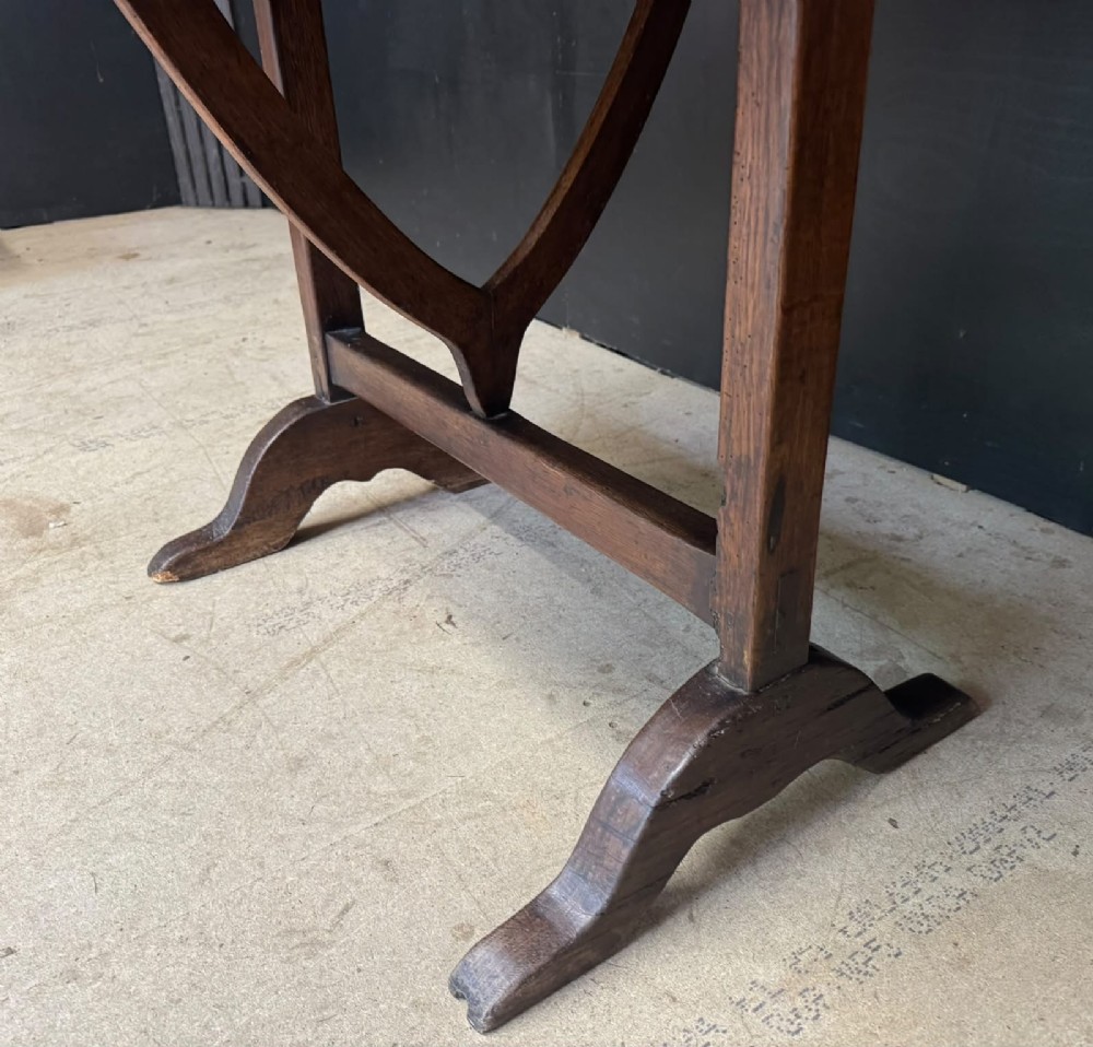 A circular French wine tasting table made of dark warm brown timber shown in a tilted position on a trestle base. View VIII