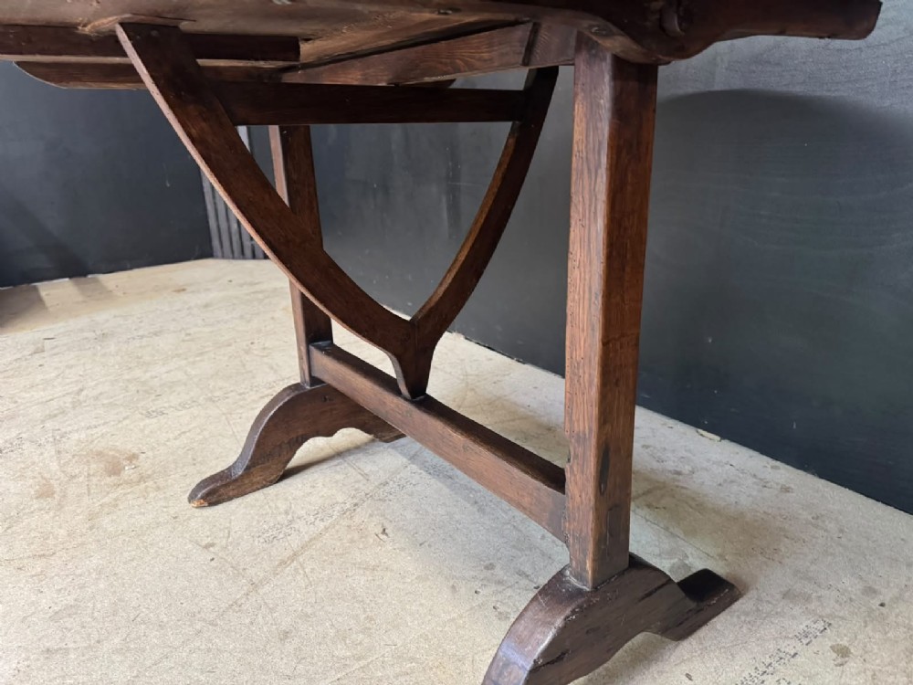 A circular French wine tasting table made of dark warm brown timber shown in a tilted position on a trestle base. View IX