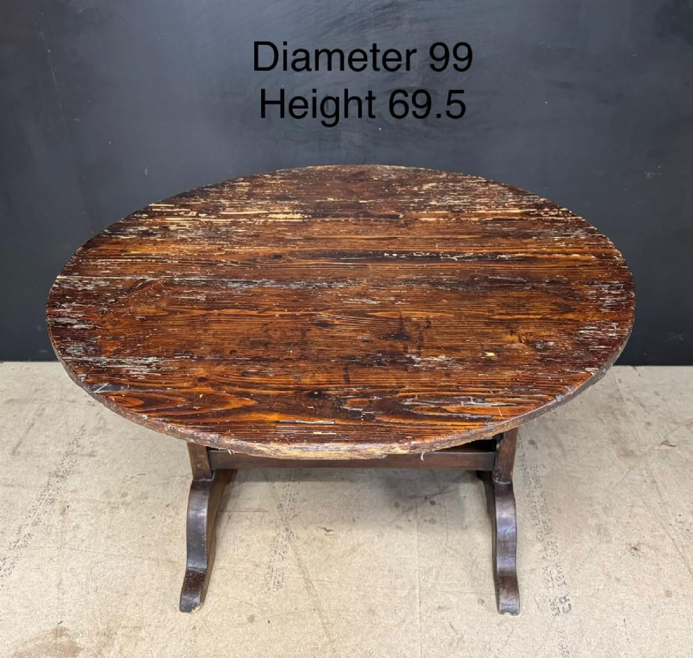 A circular French wine tasting table made of dark warm brown timber shown in a tilted position on a trestle base. View X