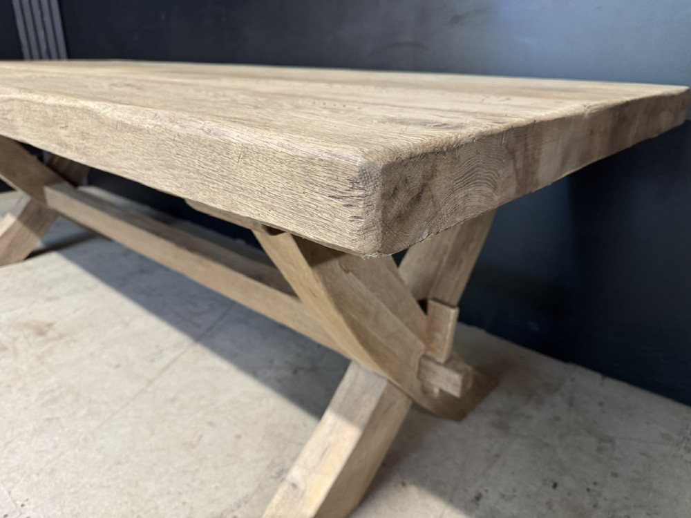 A large solid light oak dining table featuring an X-frame trestle base and a central key-joined stretcher. View X