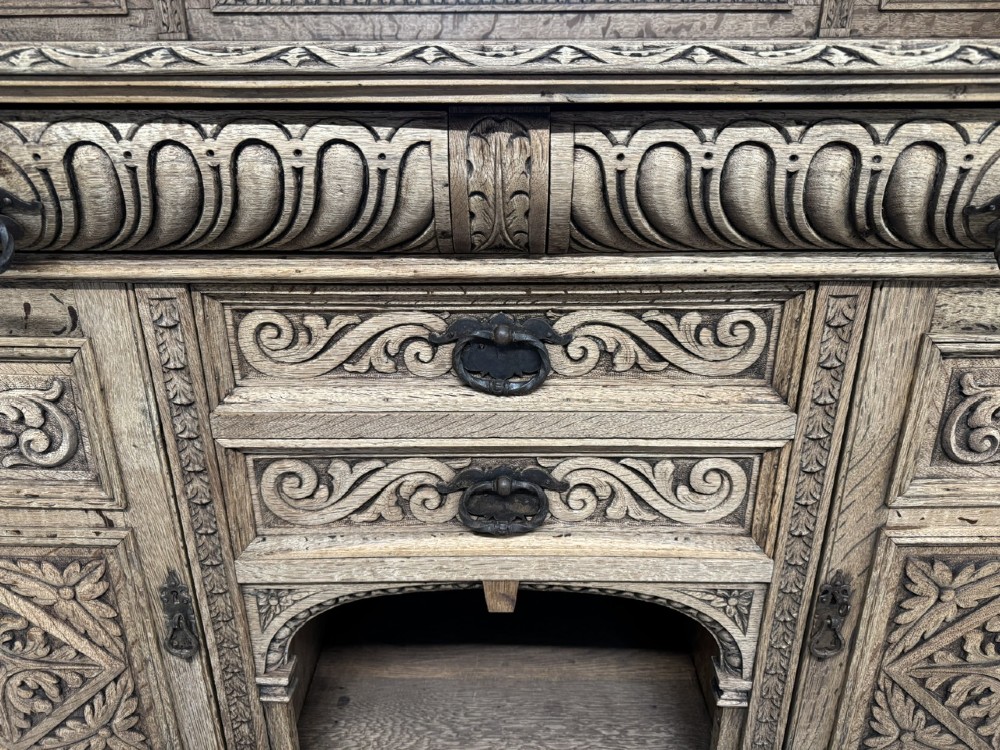 A large carved light oak sideboard with an upper cupboard section, a central mirror plate, turned columns, and detailed relief carvings throughout. View V