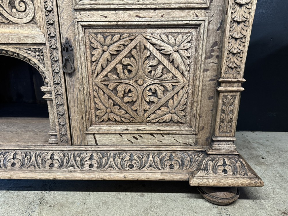 A large carved light oak sideboard with an upper cupboard section, a central mirror plate, turned columns, and detailed relief carvings throughout. View VI