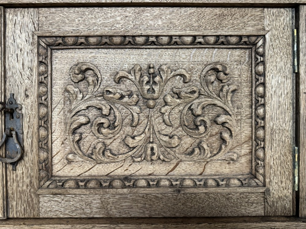 A large carved light oak sideboard with an upper cupboard section, a central mirror plate, turned columns, and detailed relief carvings throughout. View VII