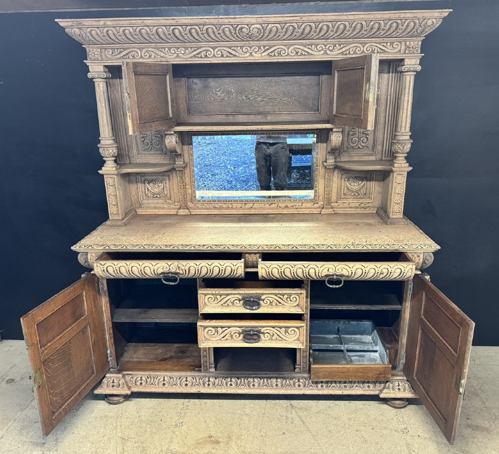 A large carved light oak sideboard with an upper cupboard section, a central mirror plate, turned columns, and detailed relief carvings throughout. View XI
