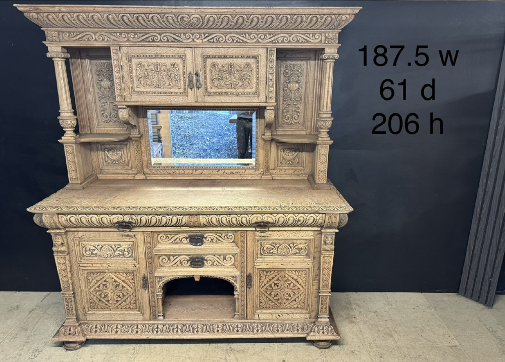 A large carved light oak sideboard with an upper cupboard section, a central mirror plate, turned columns, and detailed relief carvings throughout. View XIV