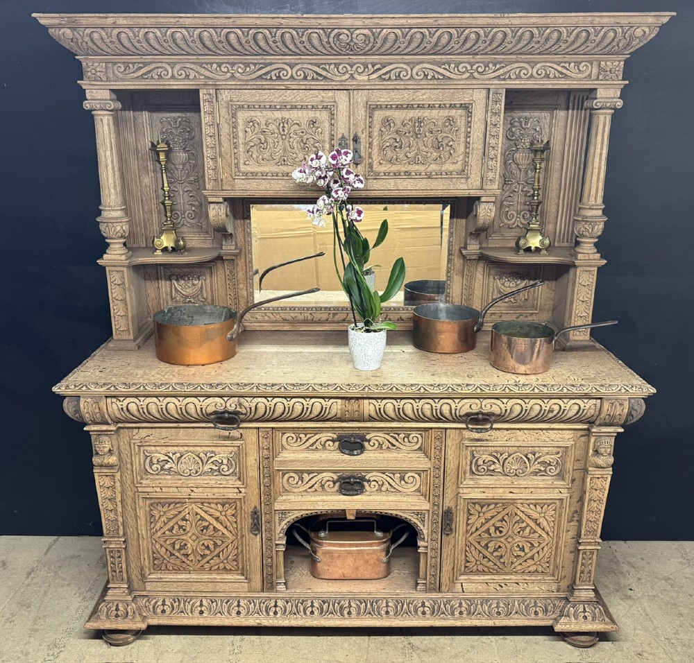 A large carved light oak sideboard with an upper cupboard section, a central mirror plate, turned columns, and detailed relief carvings throughout. View XV