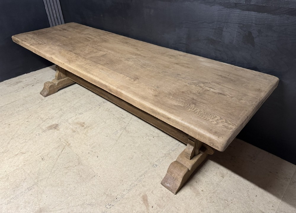 A long French oak trestle dining table featuring a thick wooden top, robust pedestal supports, and a central stretcher with pegged joints. View II