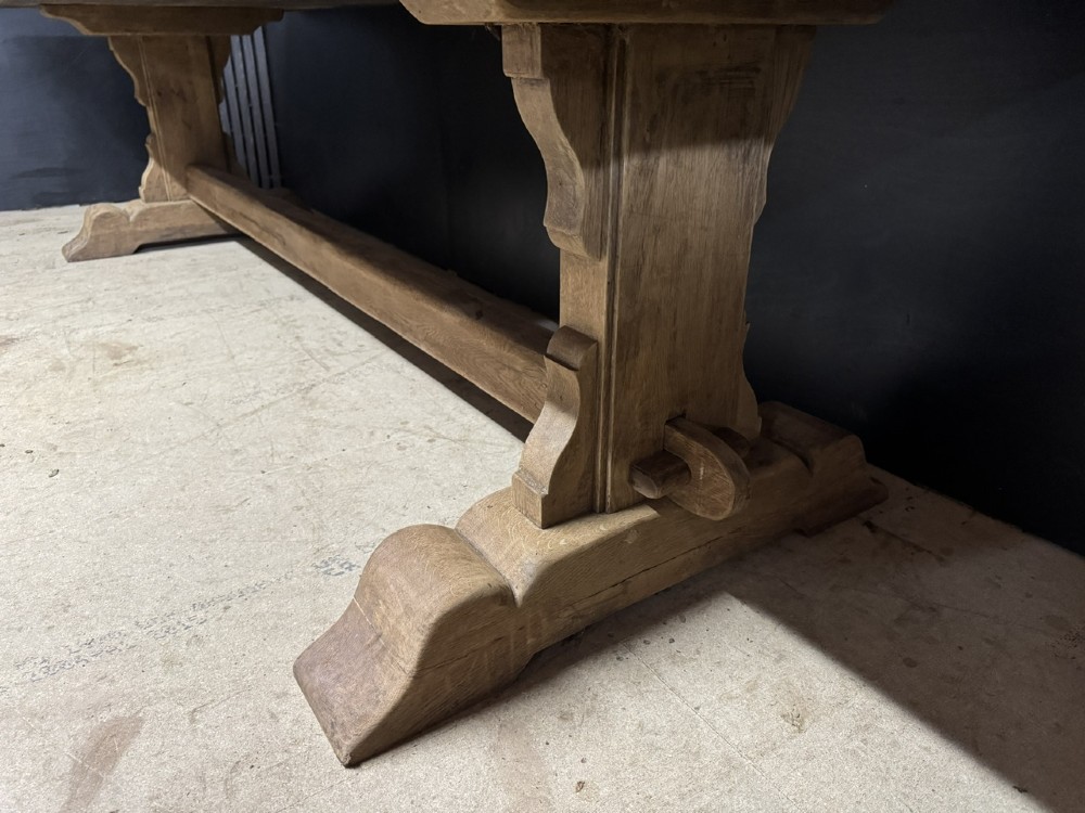 A long French oak trestle dining table featuring a thick wooden top, robust pedestal supports, and a central stretcher with pegged joints. View VIII