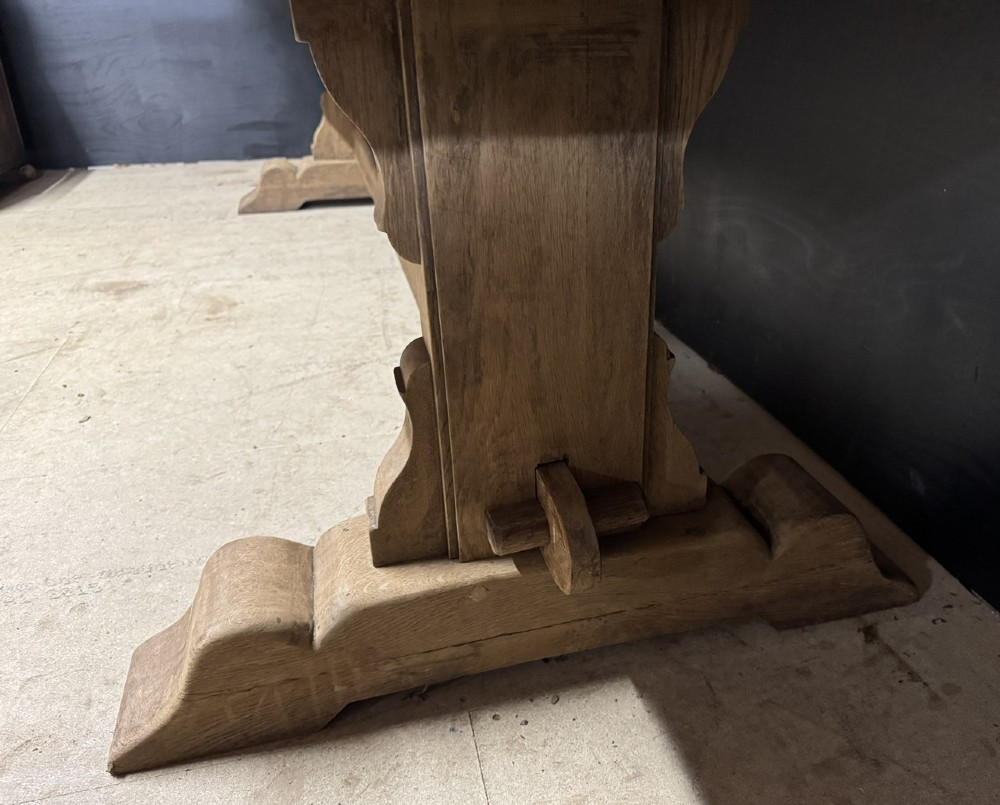 A long French oak trestle dining table featuring a thick wooden top, robust pedestal supports, and a central stretcher with pegged joints. View X