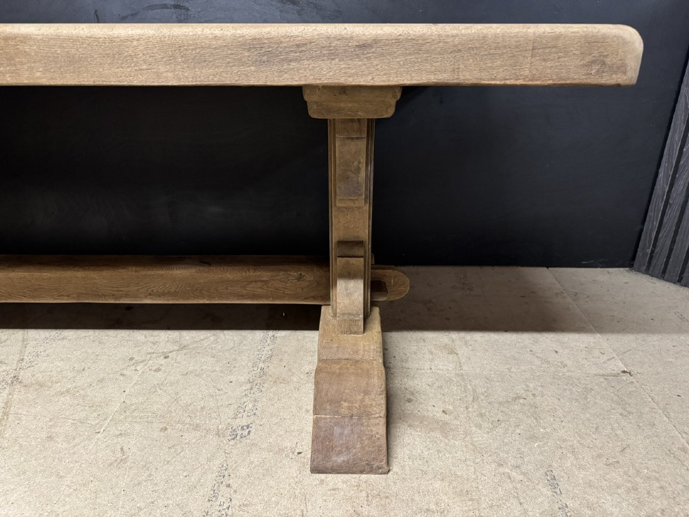 A long French oak trestle dining table featuring a thick wooden top, robust pedestal supports, and a central stretcher with pegged joints. View XII