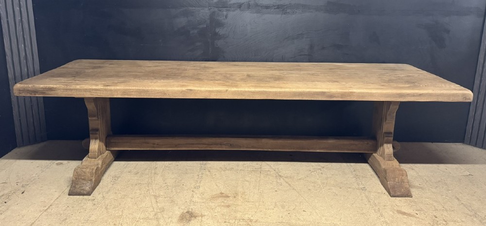 A long French oak trestle dining table featuring a thick wooden top, robust pedestal supports, and a central stretcher with pegged joints. View XV
