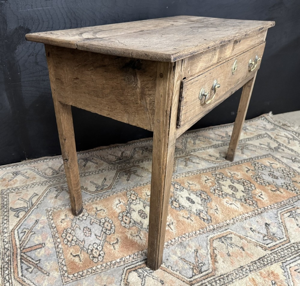 A Georgian natural oak side table with a wide single drawer, two brass swan-neck handles, a brass escutcheon, and four straight square legs. View VII