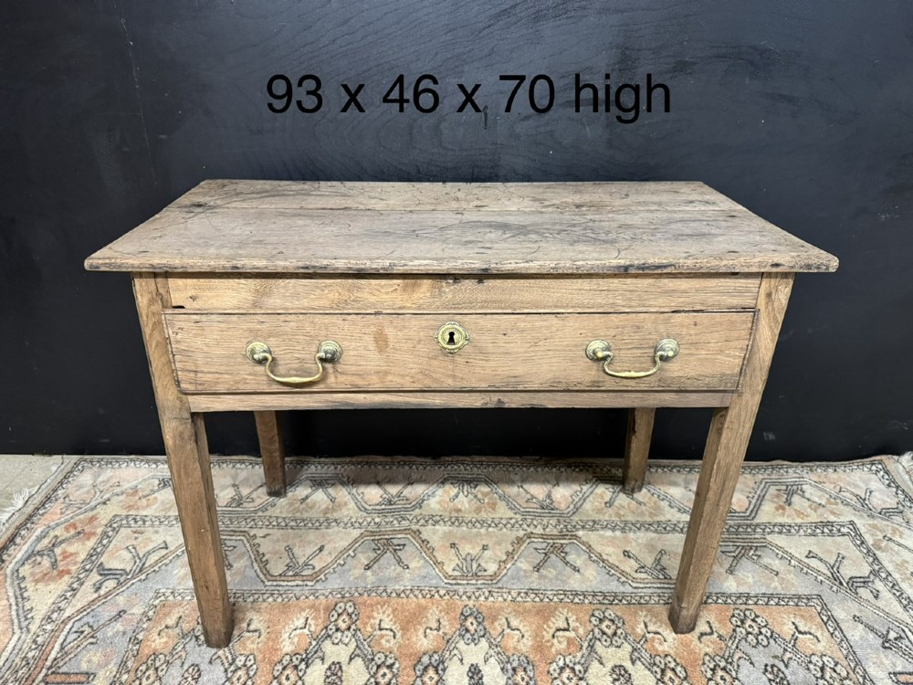 A Georgian natural oak side table with a wide single drawer, two brass swan-neck handles, a brass escutcheon, and four straight square legs. View XIII