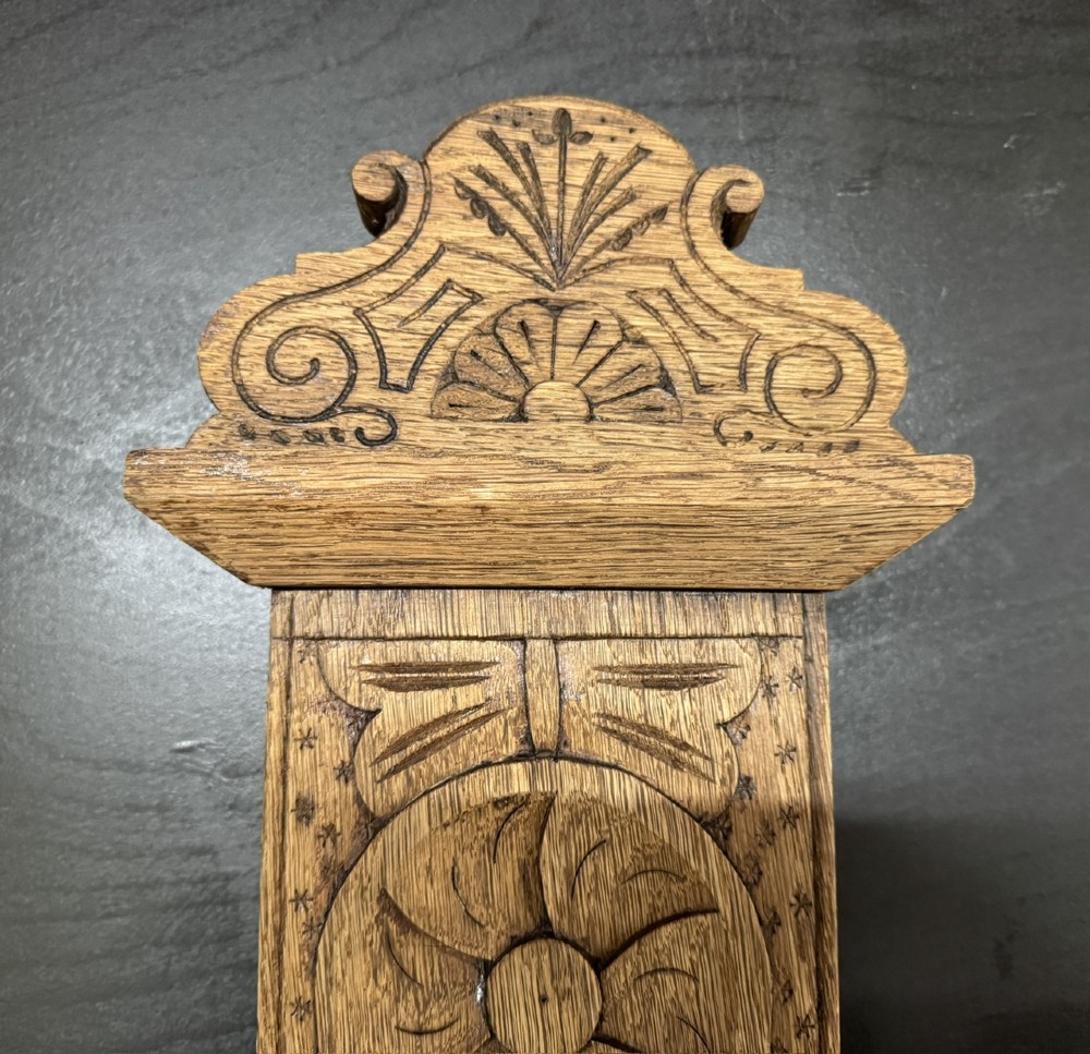 A tall carved oak hall stand featuring two horizontal rails of turned coat pegs, a central column carved with floral rosettes, bobbin-turned legs, and lower umbrella drip trays. View VIII