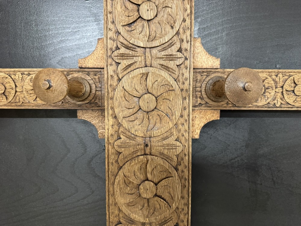 A tall carved oak hall stand featuring two horizontal rails of turned coat pegs, a central column carved with floral rosettes, bobbin-turned legs, and lower umbrella drip trays. View IX