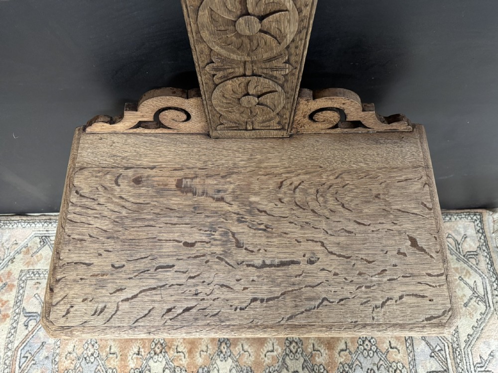 A tall carved oak hall stand featuring two horizontal rails of turned coat pegs, a central column carved with floral rosettes, bobbin-turned legs, and lower umbrella drip trays. View X