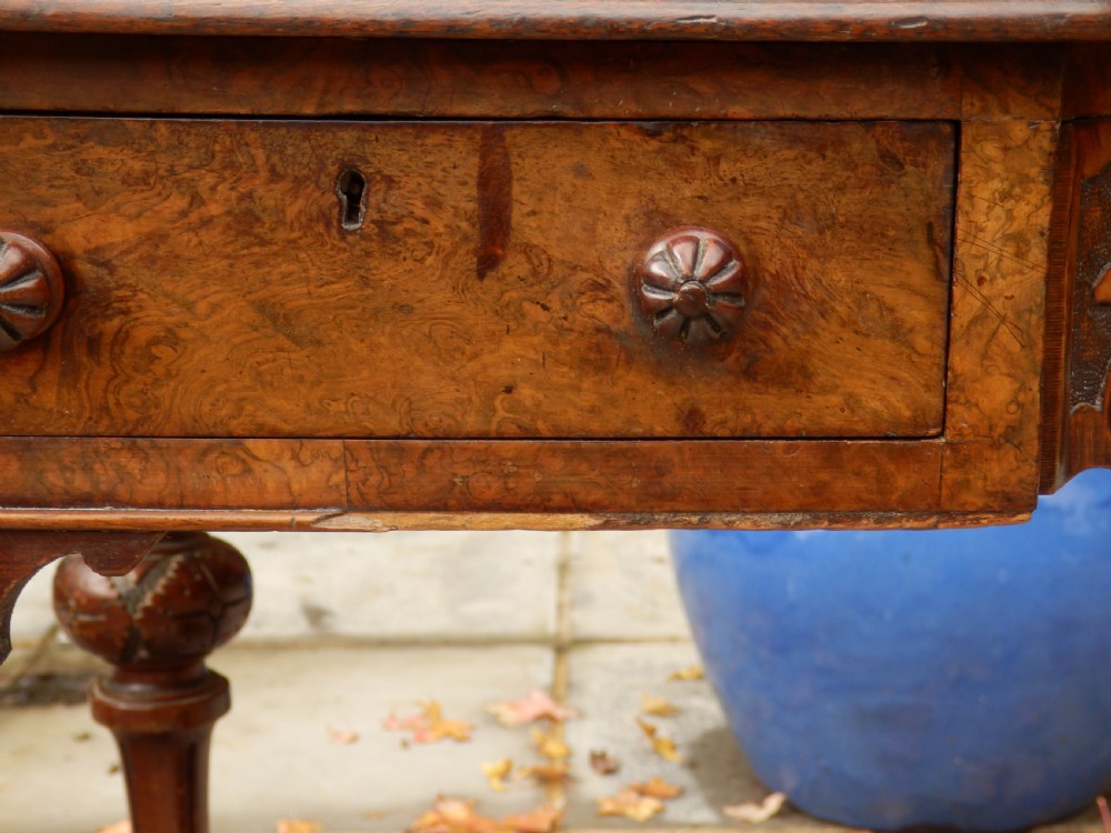 An early Victorian burr walnut writing desk featuring an inset leather writing top, carved frieze drawers, turned legs, and a raised central rear plinth. View XII