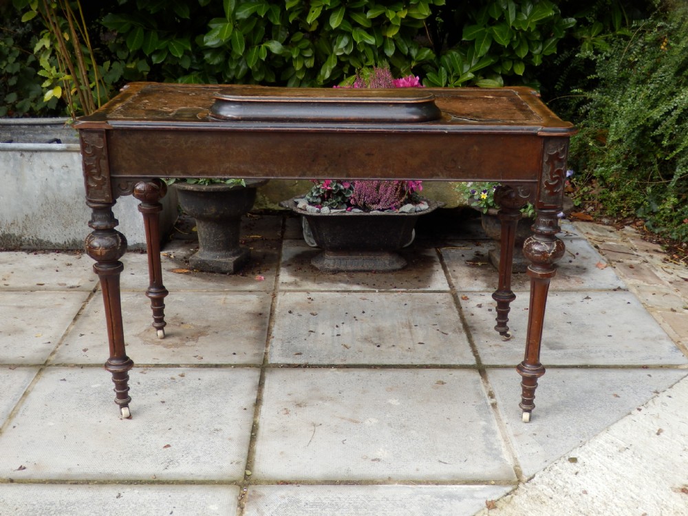 An early Victorian burr walnut writing desk featuring an inset leather writing top, carved frieze drawers, turned legs, and a raised central rear plinth. View XIII
