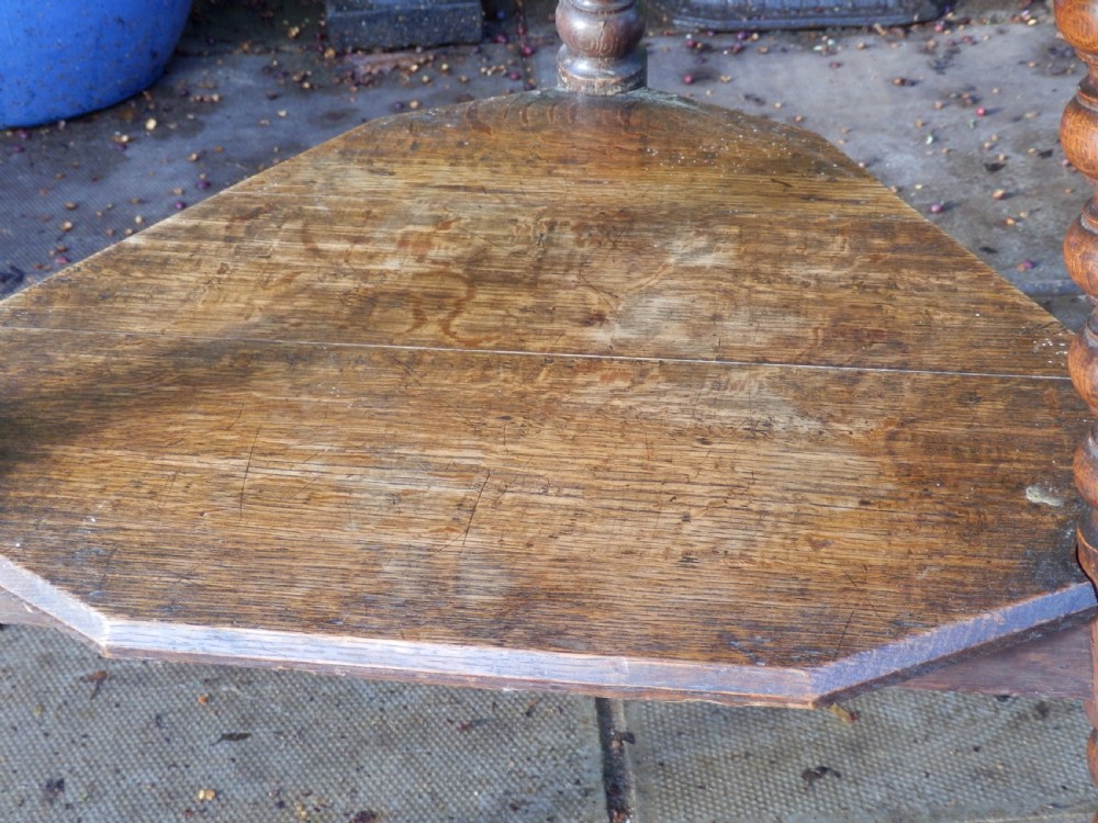 An oak Arts and Crafts octagonal side table featuring four bobbin turned legs and an open lower shelf tier. View II