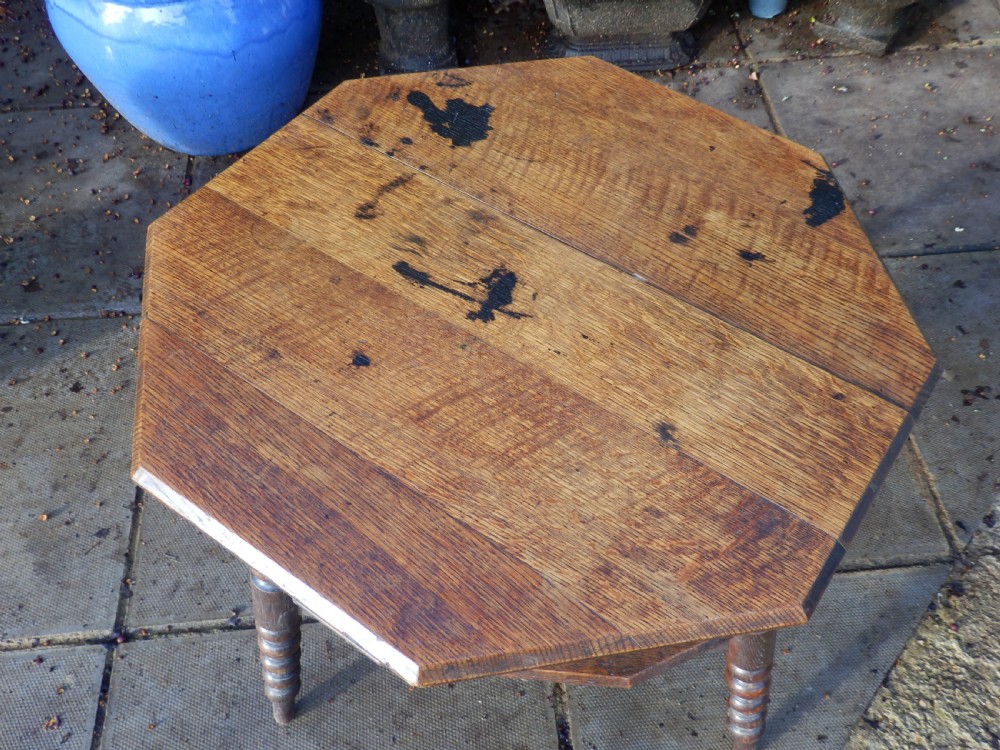 An oak Arts and Crafts octagonal side table featuring four bobbin turned legs and an open lower shelf tier. View V