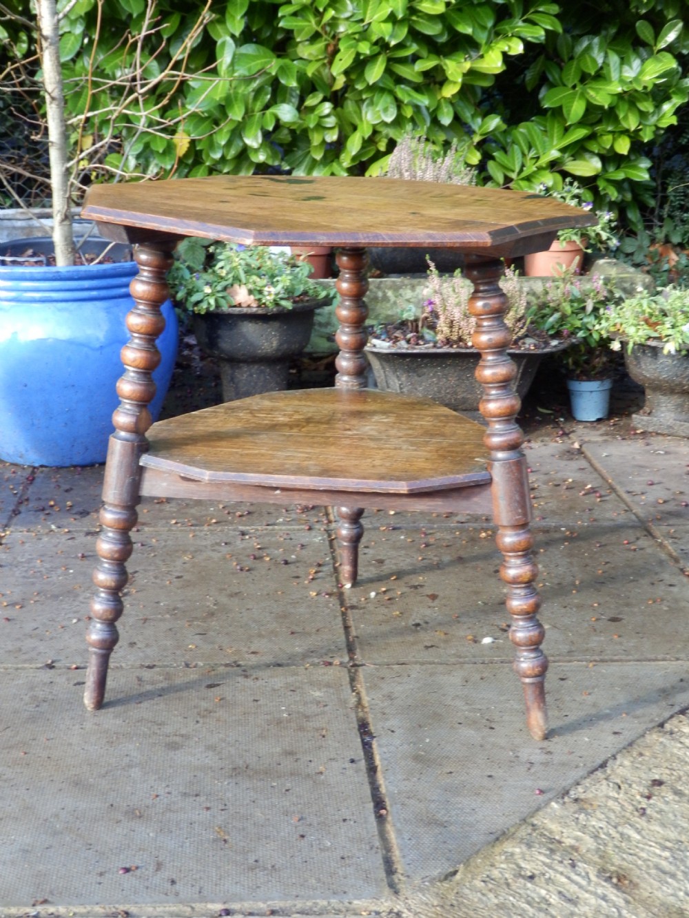 An oak Arts and Crafts octagonal side table featuring four bobbin turned legs and an open lower shelf tier.
