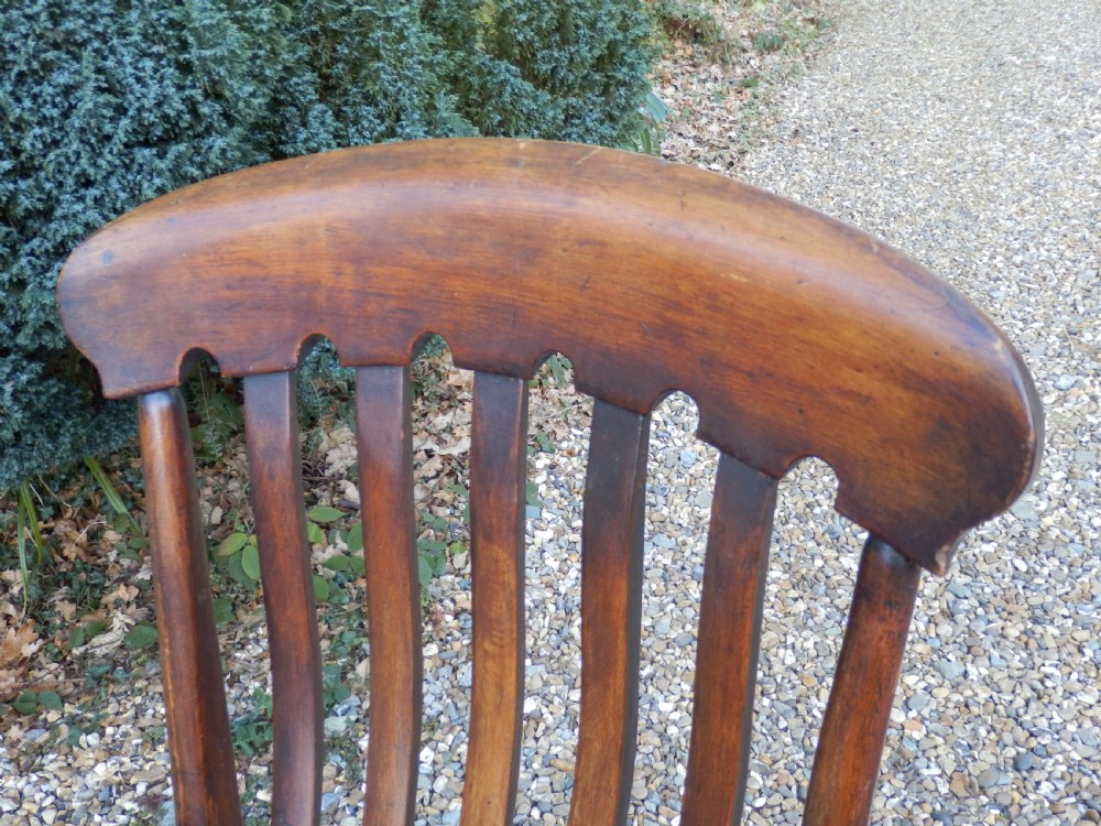 A Victorian wooden Windsor carver armchair featuring a high slat back, turned front legs, curved armrests, and a saddle seat in a dark brown timber finish. View IV
