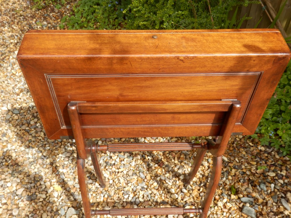 A Victorian mahogany folding writing desk featuring curved X-frame legs, an open writing tray top with a leather insert, and a built-in inkwell compartment. View VI