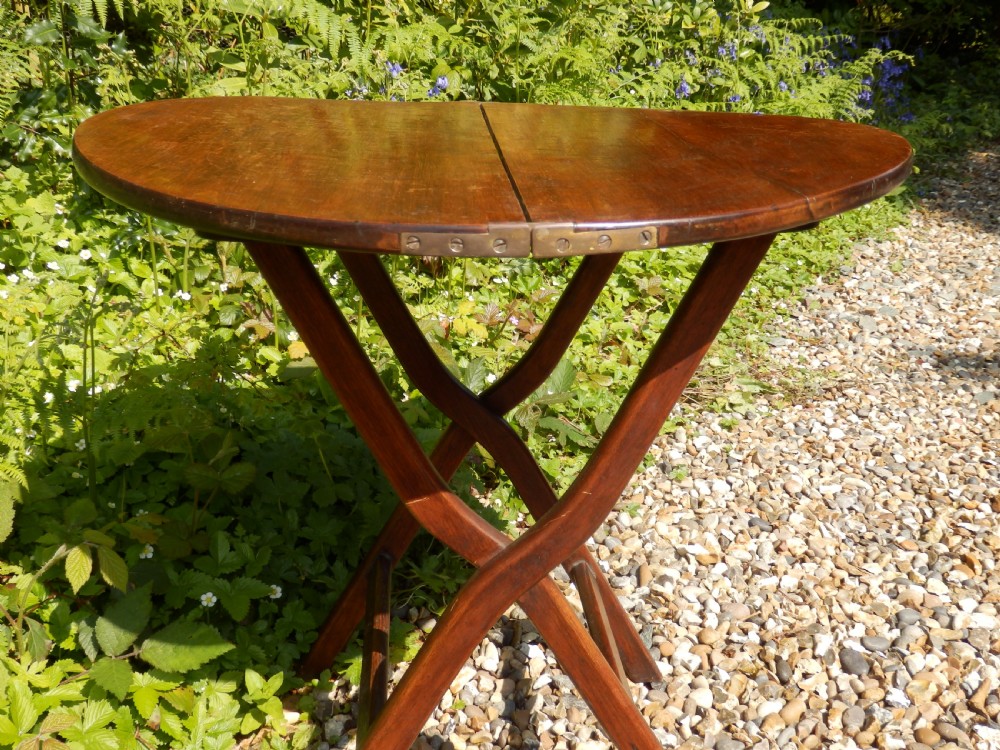 A Victorian mahogany folding coaching table featuring a circular top supported by an X-frame leg assembly with brass rim hinges. View V