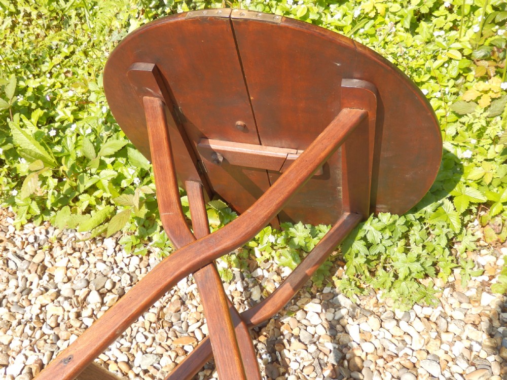 A Victorian mahogany folding coaching table featuring a circular top supported by an X-frame leg assembly with brass rim hinges. View VI