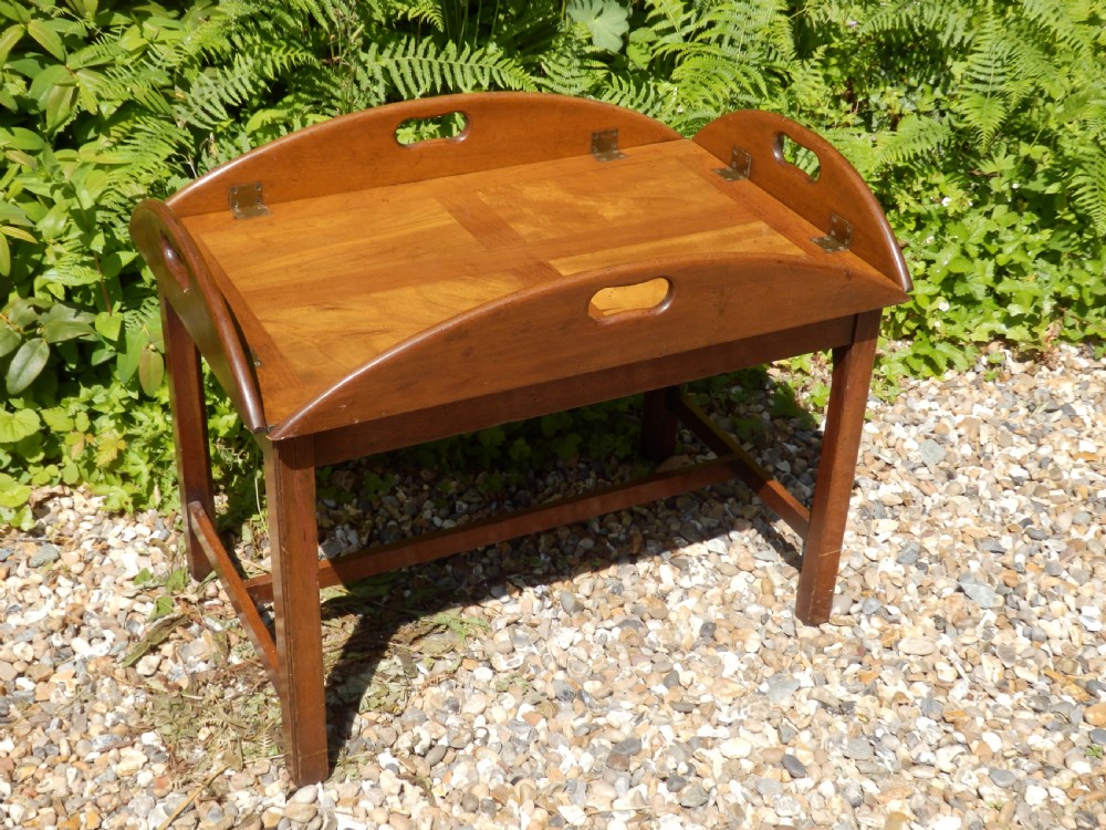 A Victorian mahogany butlers tray featuring four hinged curved sides with cut-out handles, set upon a low wooden stand. View III