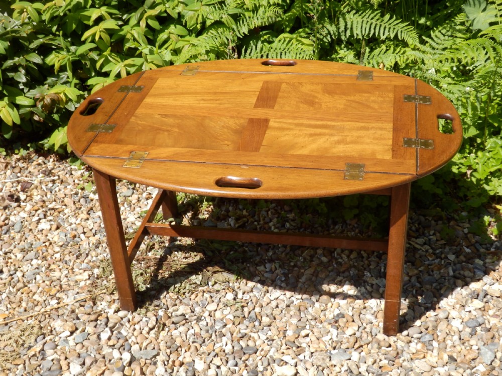 A Victorian mahogany butlers tray featuring four hinged curved sides with cut-out handles, set upon a low wooden stand. View V
