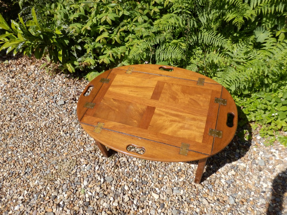 A Victorian mahogany butlers tray featuring four hinged curved sides with cut-out handles, set upon a low wooden stand. View VI