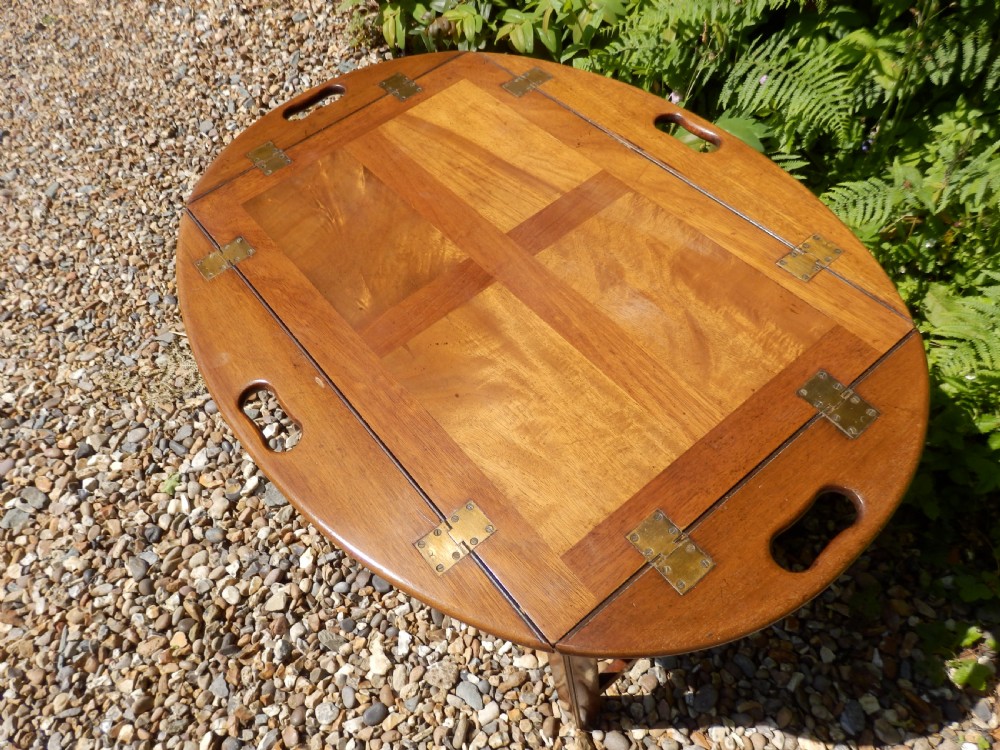 A Victorian mahogany butlers tray featuring four hinged curved sides with cut-out handles, set upon a low wooden stand. View VII