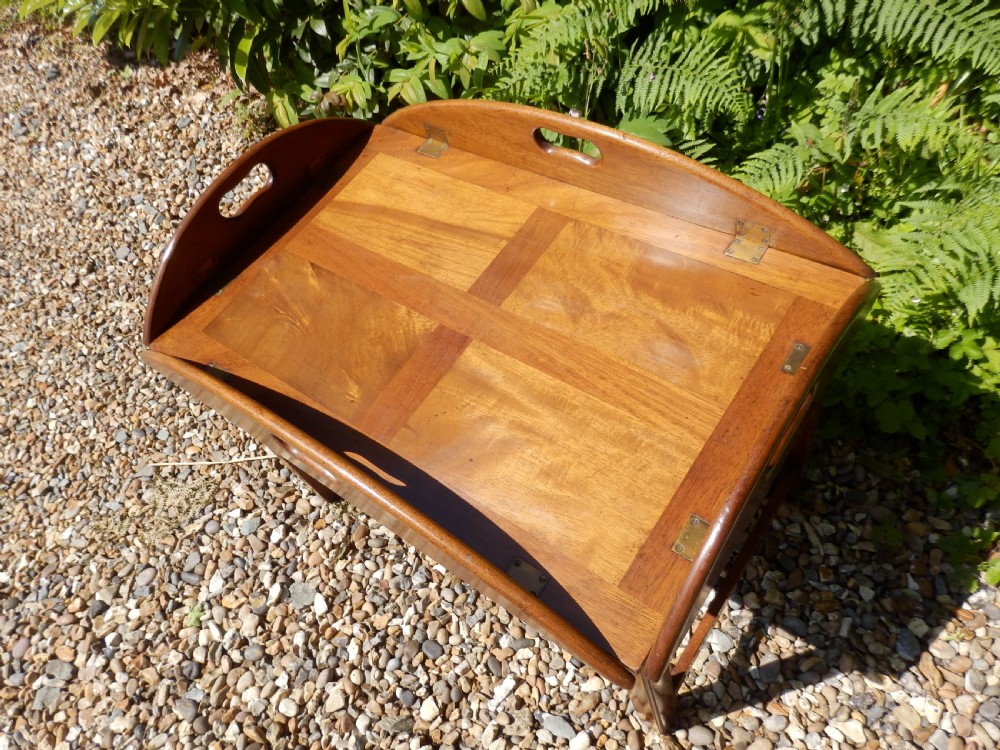 A Victorian mahogany butlers tray featuring four hinged curved sides with cut-out handles, set upon a low wooden stand. View VIII