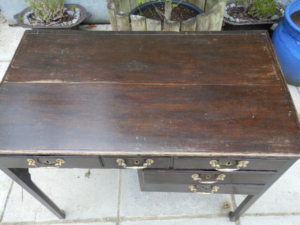A Victorian dark wood writing desk featuring five drawers with brass swan-neck handles and brass keyhole escutcheons, supported by slender legs on small castors. View IV