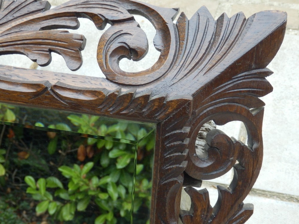 An Edwardian rectangular wall mirror set within a dark oak frame deeply carved with acanthus leaves and scrollwork motifs. View IV