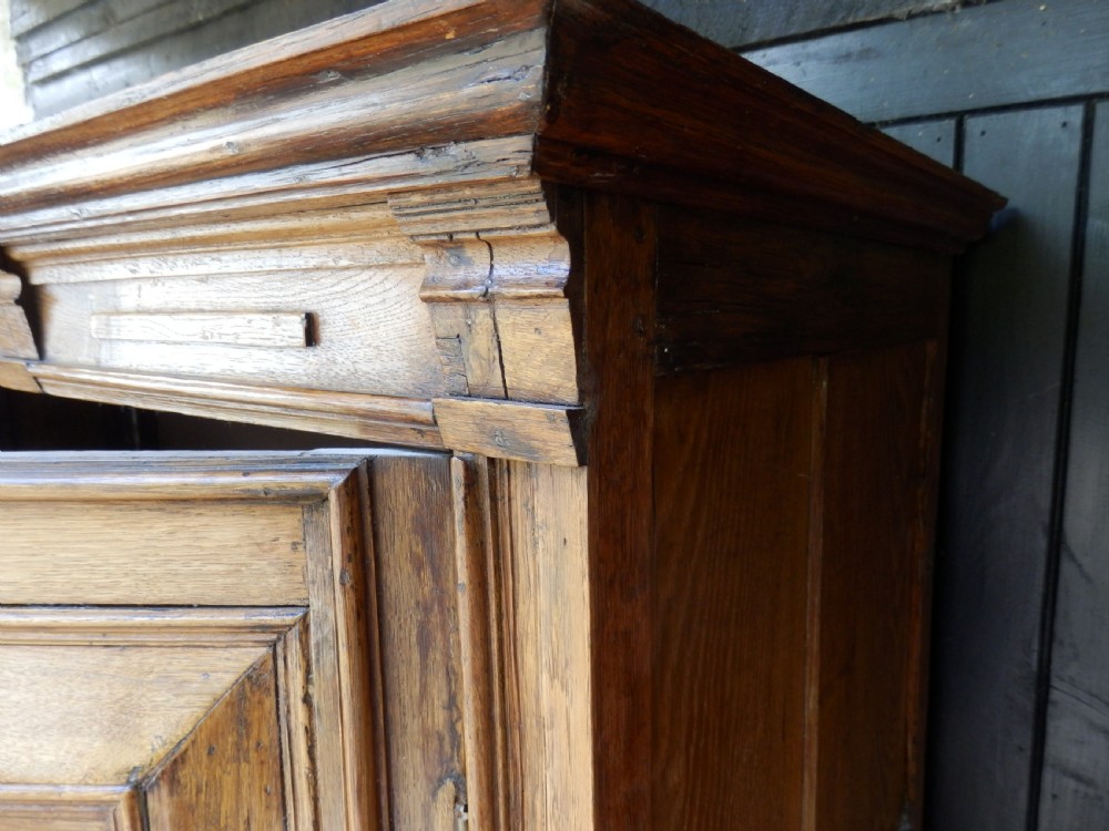An 18th-century solid oak hall cupboard featuring double doors with geometric fielded panelling, lower drawers, and a stepped top cornice. View II