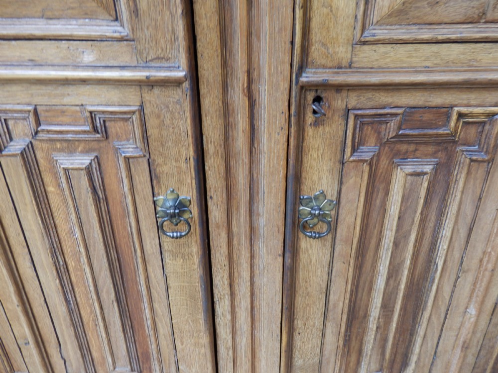 An 18th-century solid oak hall cupboard featuring double doors with geometric fielded panelling, lower drawers, and a stepped top cornice. View VI