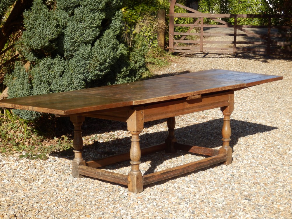 An extended antique Georgian oak dining table featuring turned legs, perimeter box stretchers, and draw-leaf extensions extending to 2.9 metres.