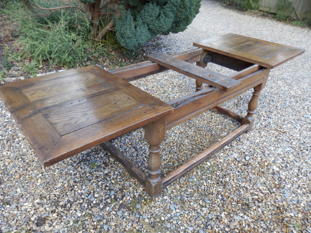 An extended antique Georgian oak dining table featuring turned legs, perimeter box stretchers, and draw-leaf extensions extending to 2.9 metres. View X