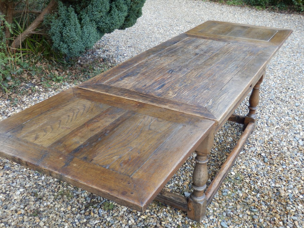 An extended antique Georgian oak dining table featuring turned legs, perimeter box stretchers, and draw-leaf extensions extending to 2.9 metres. View XI