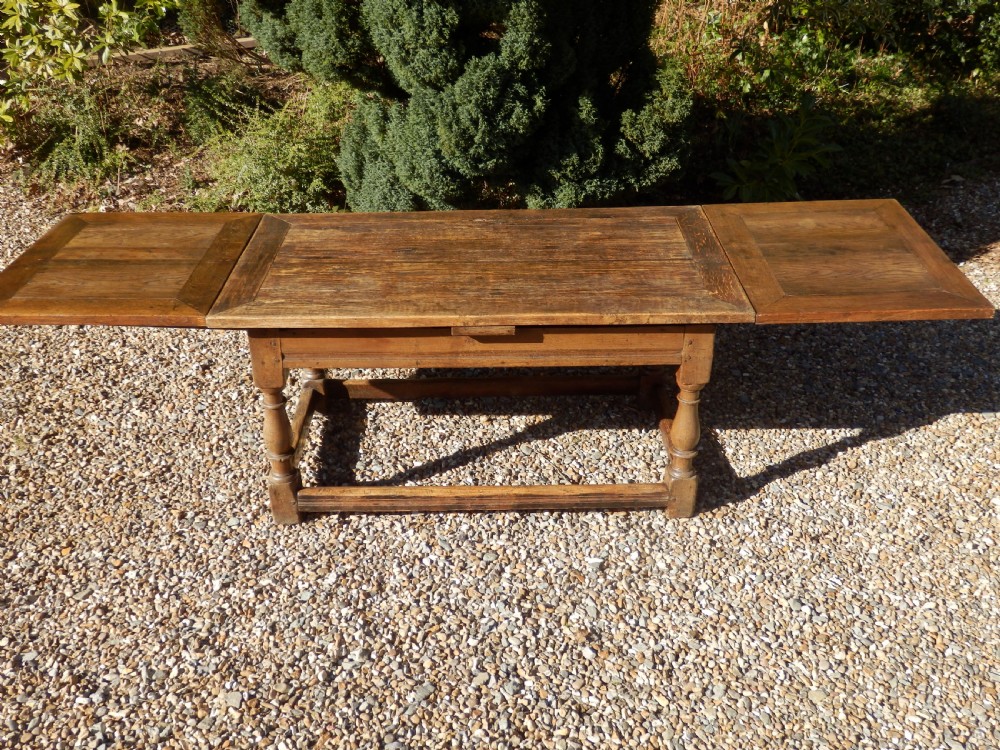 An extended antique Georgian oak dining table featuring turned legs, perimeter box stretchers, and draw-leaf extensions extending to 2.9 metres. View XVII