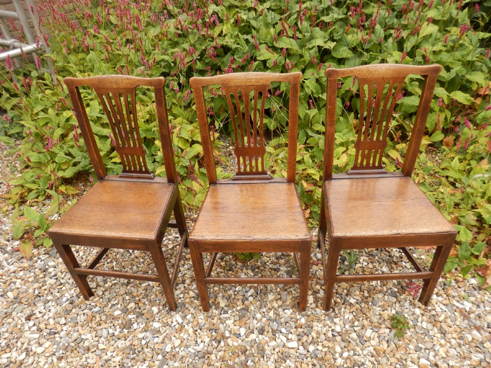 A set of six dark oak Georgian dining chairs featuring pierced vertical back splats, solid wooden seats, and straight legs connected by stretchers. View VII